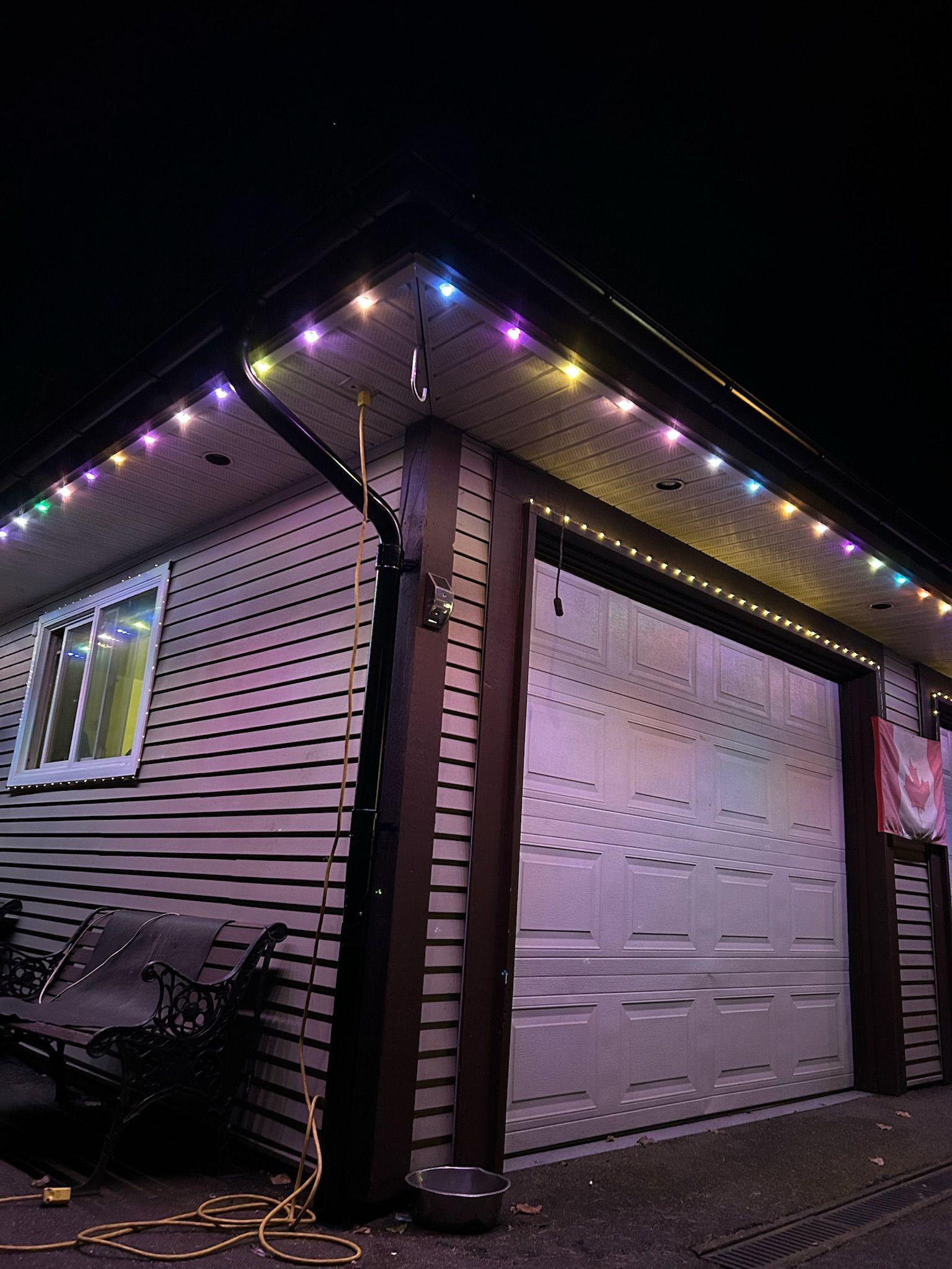A house with a garage door decorated with christmas lights at night.