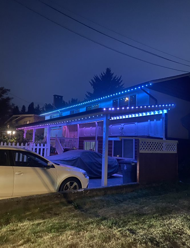A car is parked in front of a house with blue lights on the roof.
