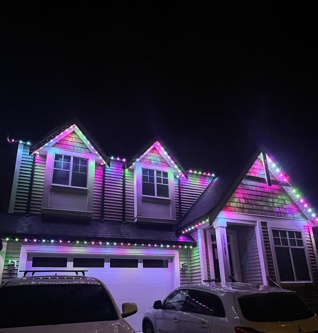 A house with christmas lights on it is lit up at night.