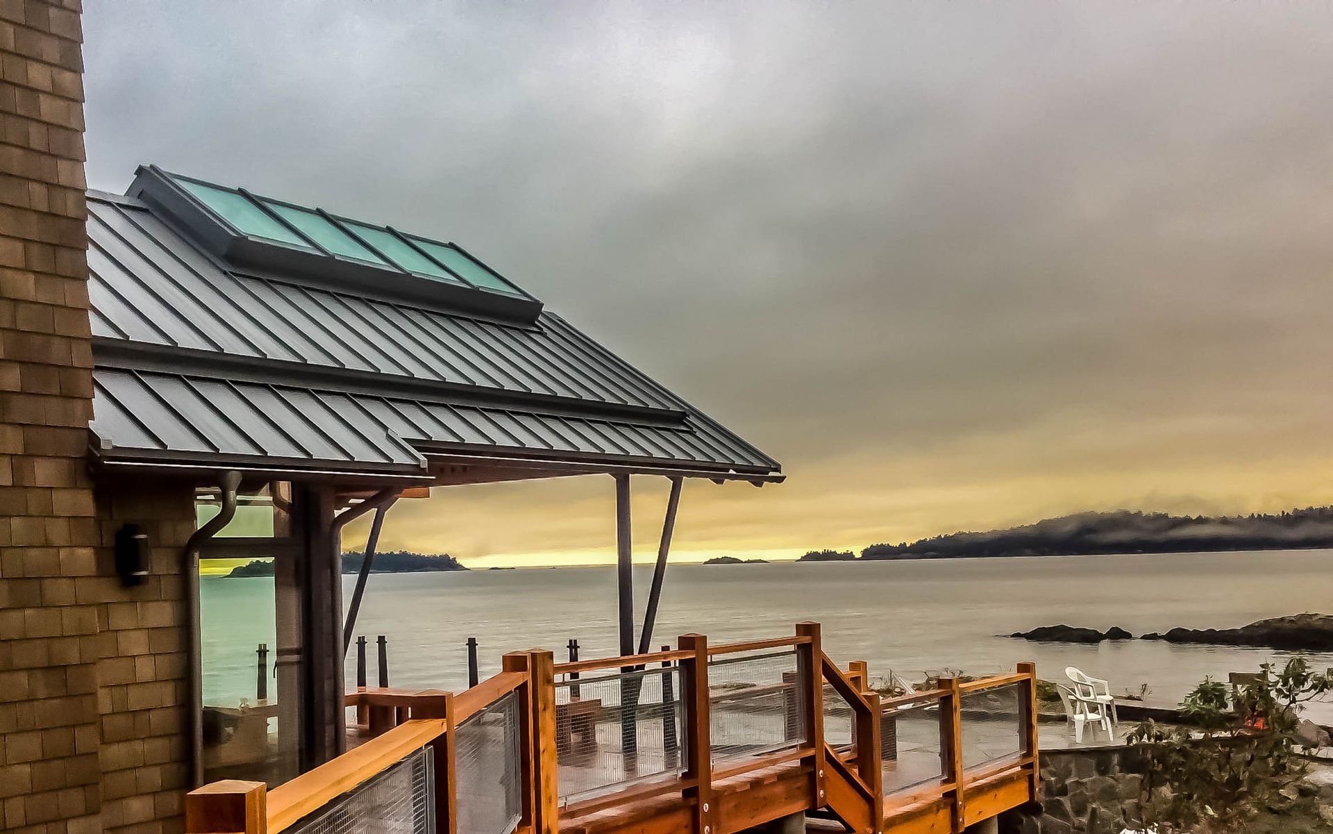 A house with a metal roof and a wooden deck overlooking the ocean.