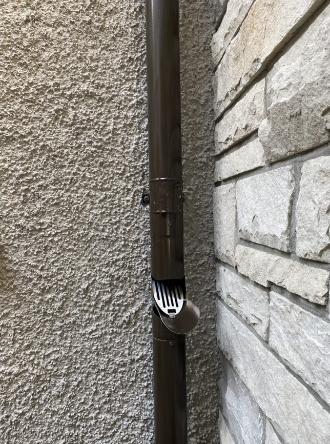 A brown pipe is sitting on the side of a brick wall.