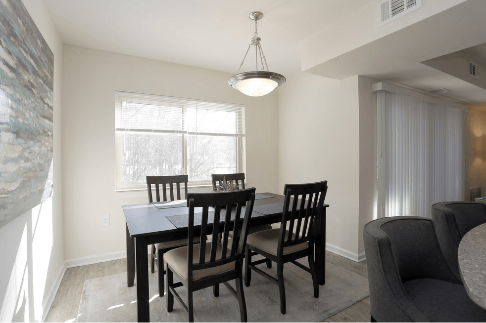 Dining room with black table, four chairs, window, and hanging light.