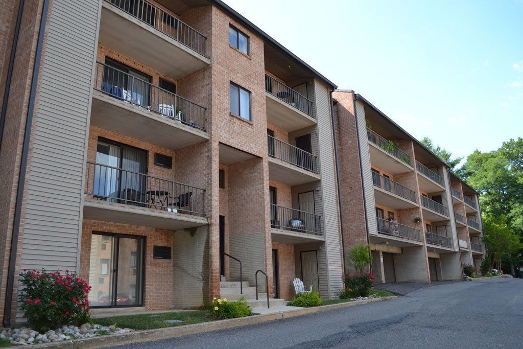 Apartment building with brick exterior and balconies on a slightly sloped asphalt road.