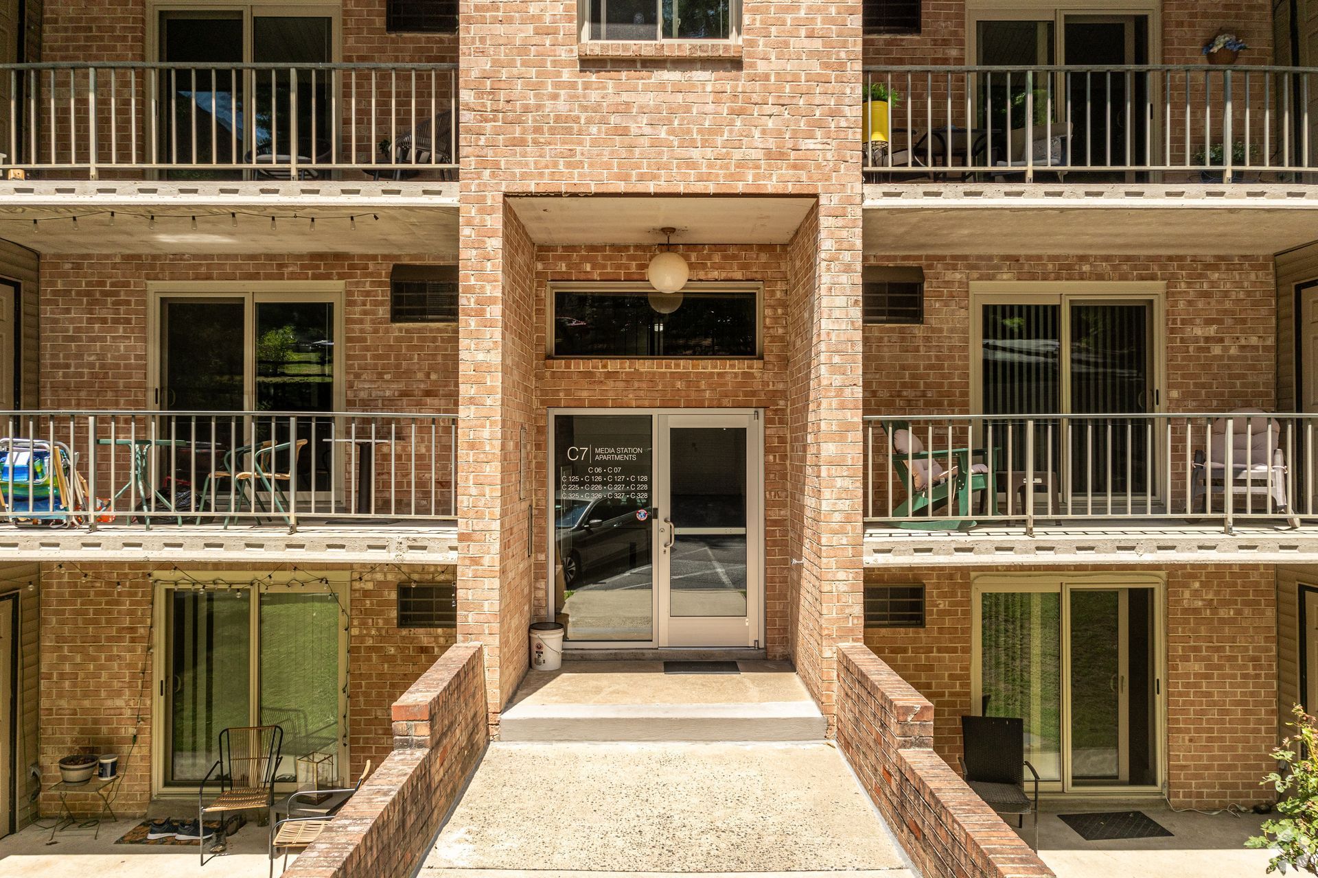 Brick apartment building exterior with balconies and front entrance.