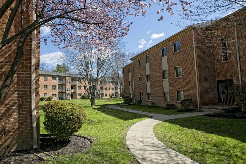 Apartment buildings with brick facades on a sunny day. A path leads through green grass.