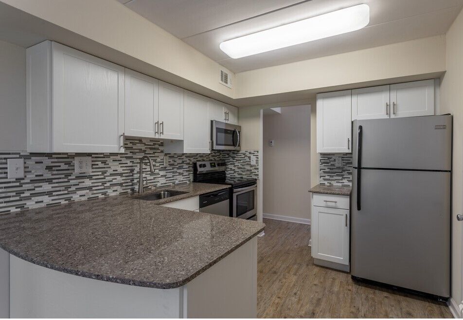 Kitchen with white cabinets, gray countertop, stainless steel appliances, and tile backsplash.