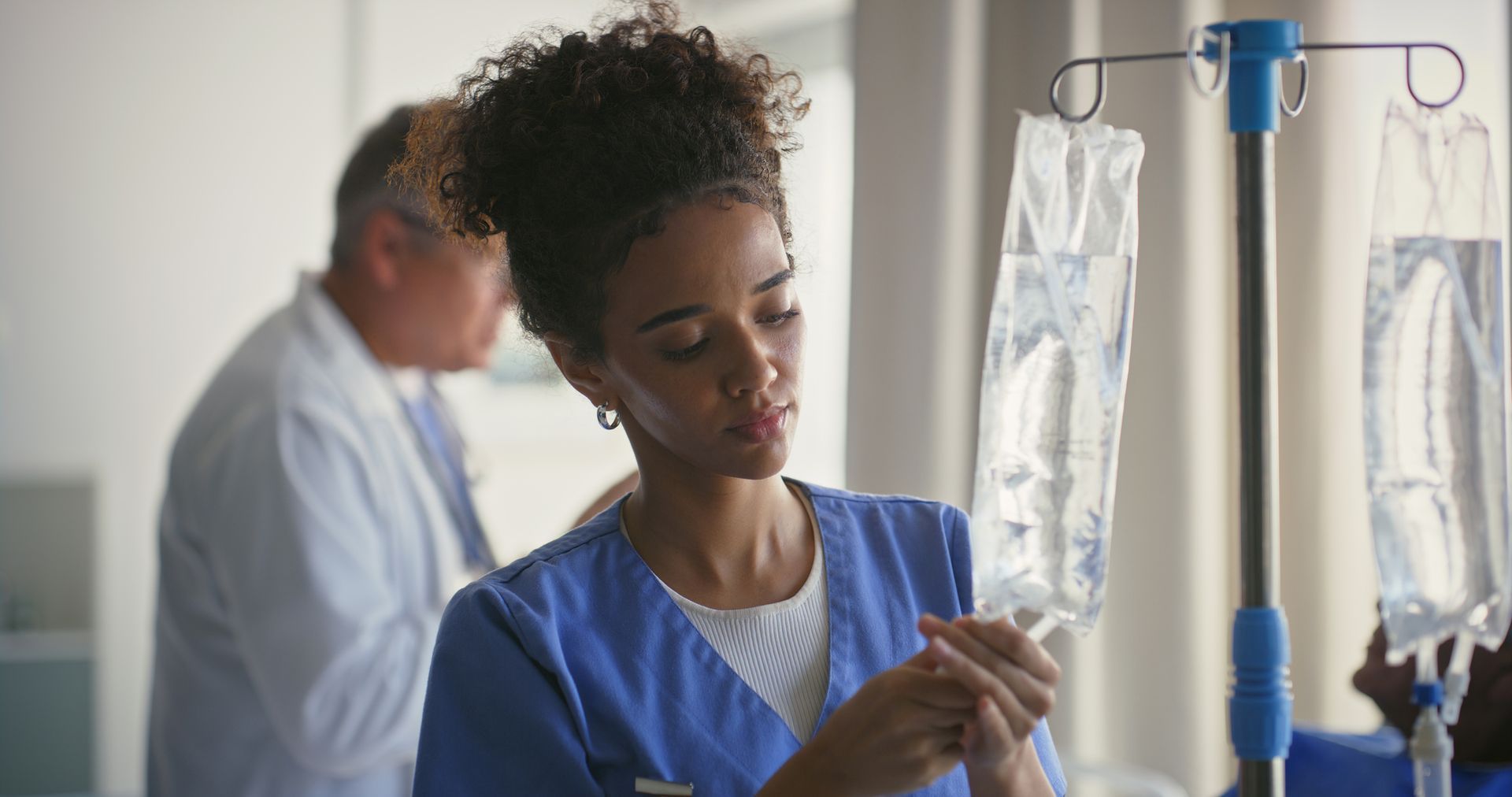 A woman with curly hair is wearing a green shirt and smiling.