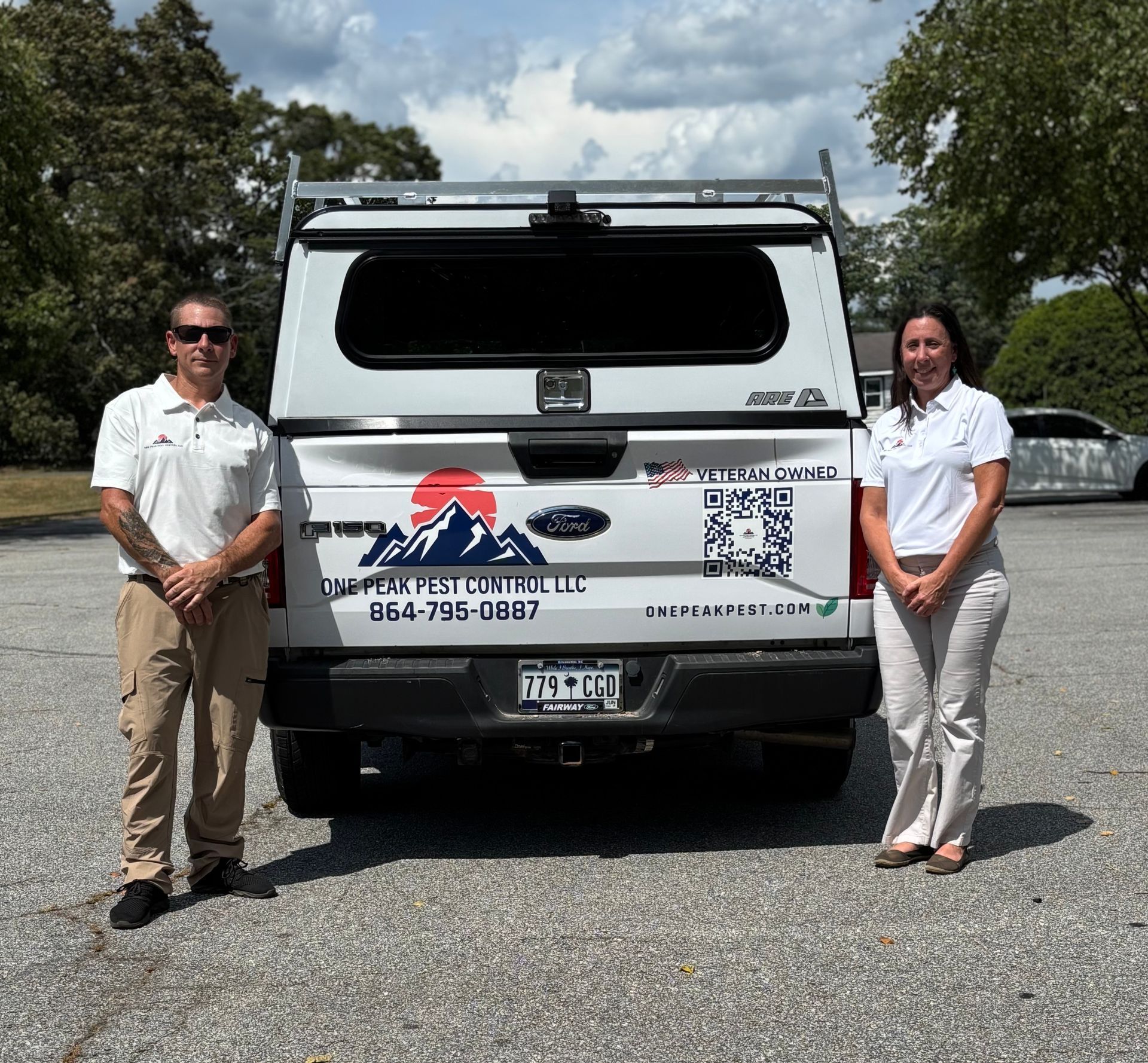 Two people standing near a white pickup truck with a pest control company logo.