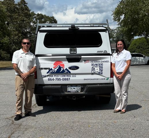 Two people standing near a white pickup truck with a pest control company logo.