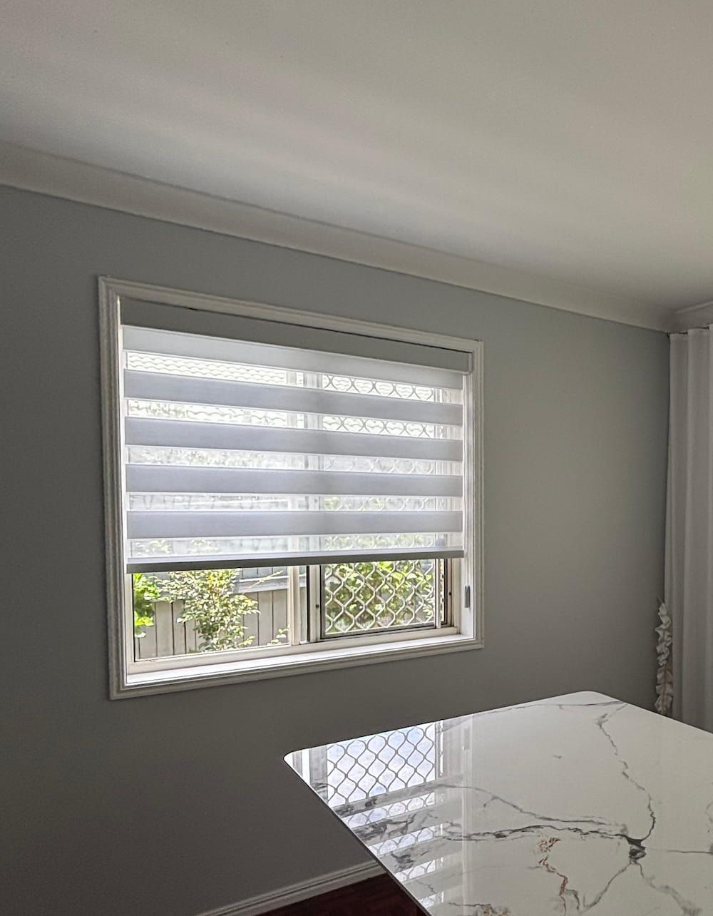A Window with Zebra Blinds Partially Open on A Light Gray Wall — U Curtains in Acacia Ridge, QLD
