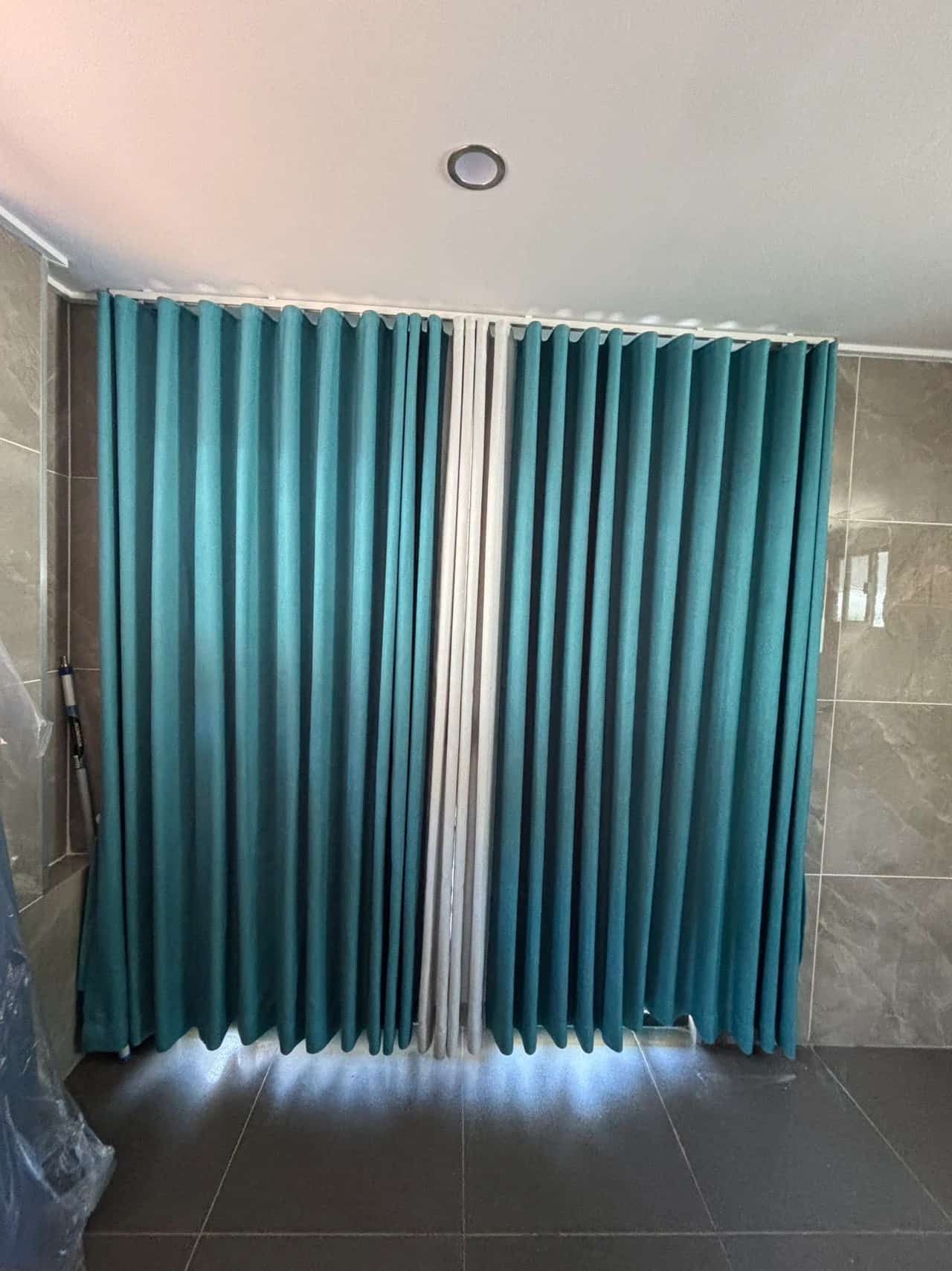 Teal Curtains Hanging in Front of A Window or Doorway with White Rods Between Them — U Curtains in Acacia Ridge, QLD