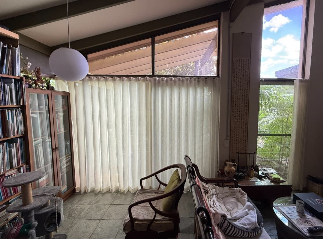 A Living Room with A Bookcase, Chairs and A Large Window with White Curtains — U Curtains in Acacia Ridge, QLD