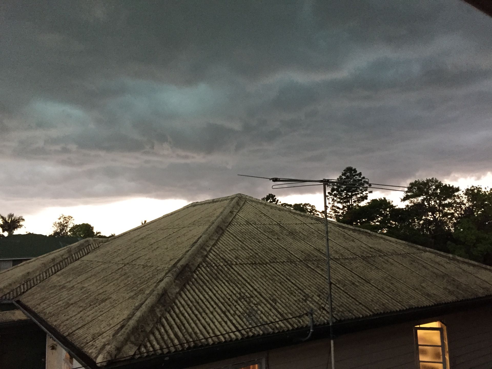 A roof of a house with a cloudy sky in the background