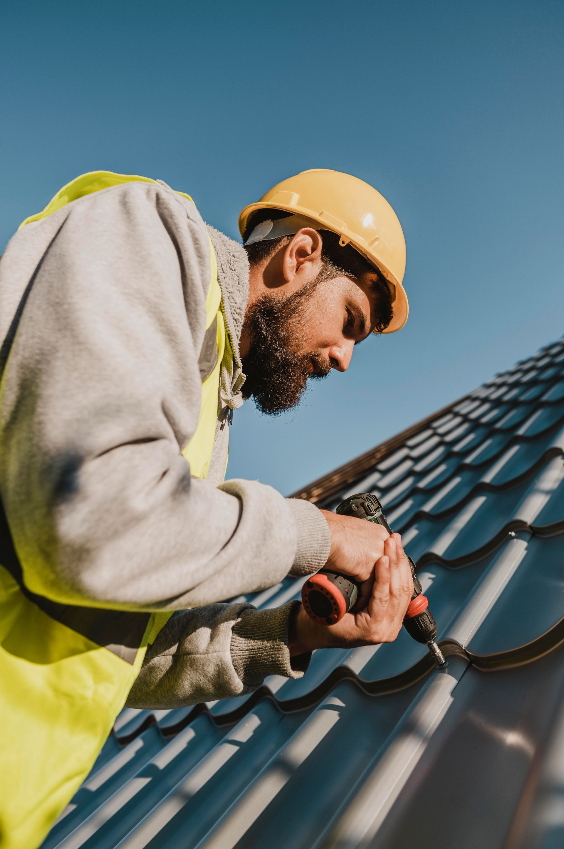 A man is working on a roof with a drill.