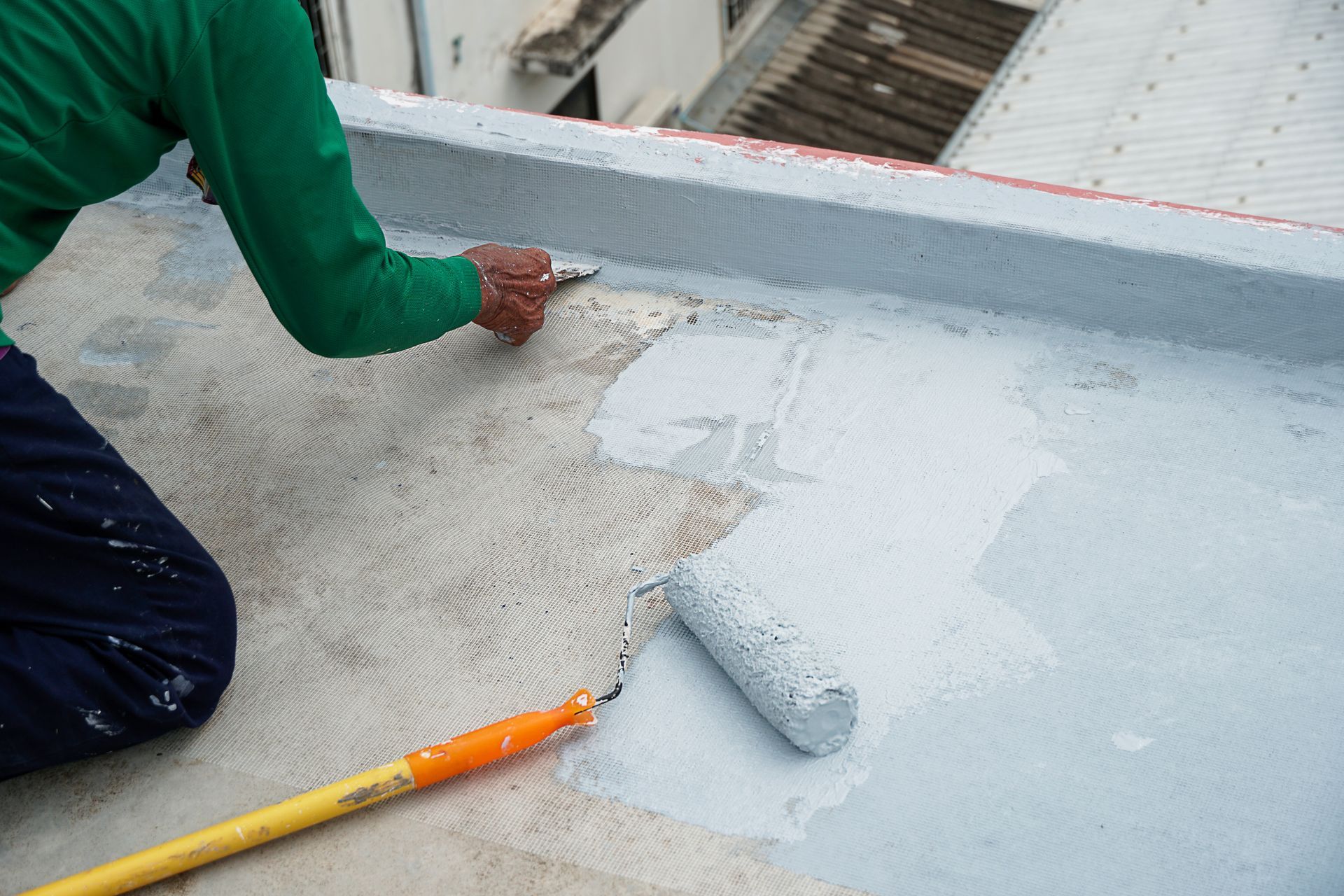 A man is painting a roof with a roller.