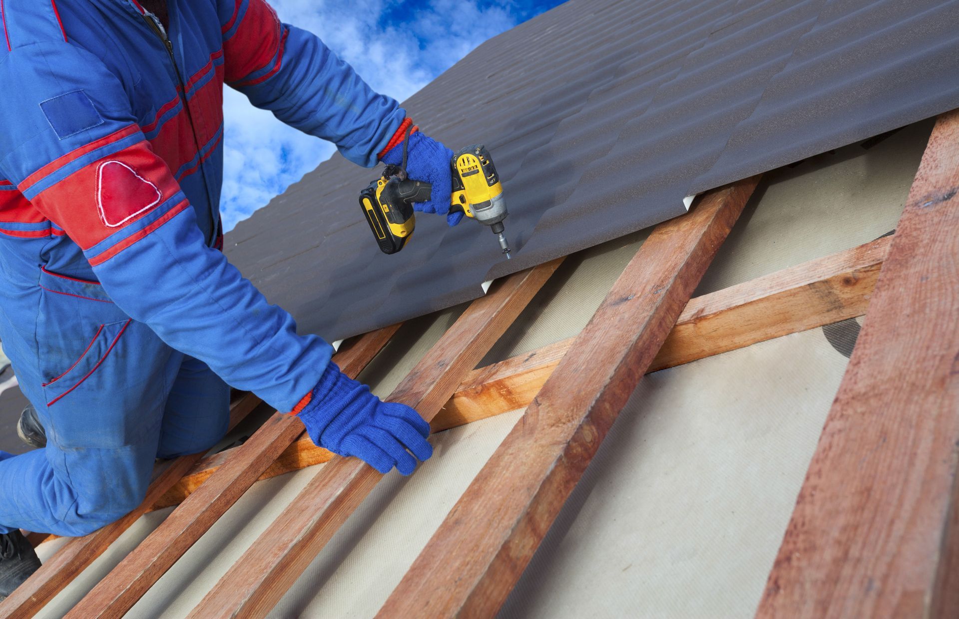 A man is working on a roof with a drill.