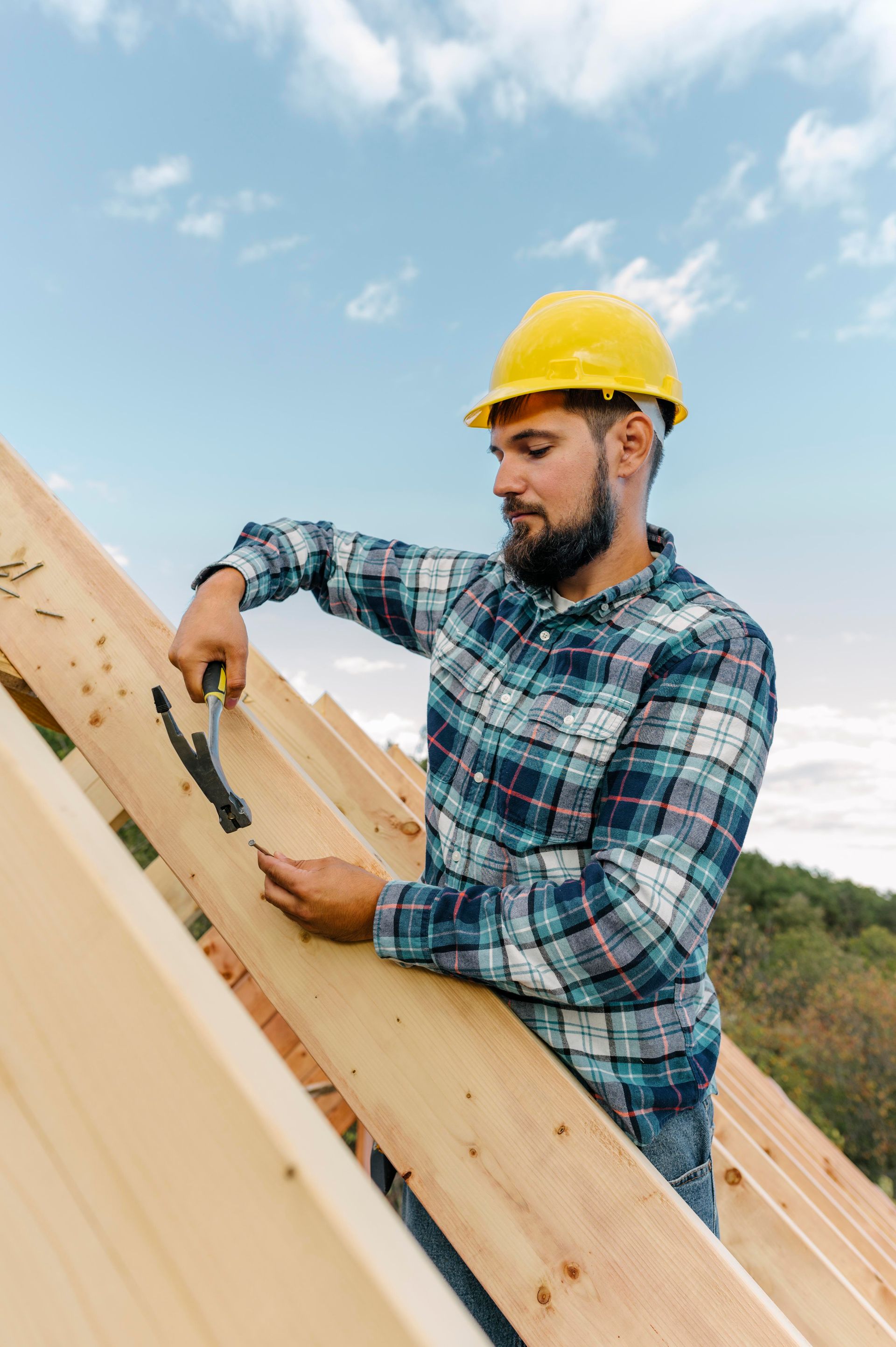 A man is working on a wooden roof with a hammer.