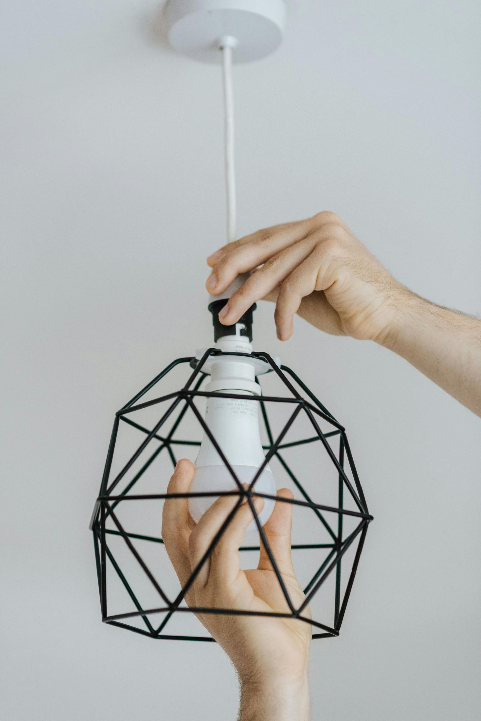 A person is changing a light bulb in a cage.