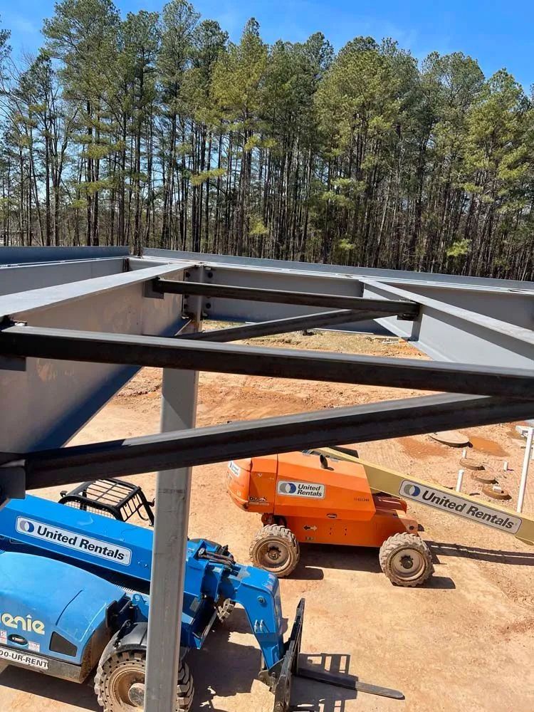 A blue and orange crane is parked under a metal structure