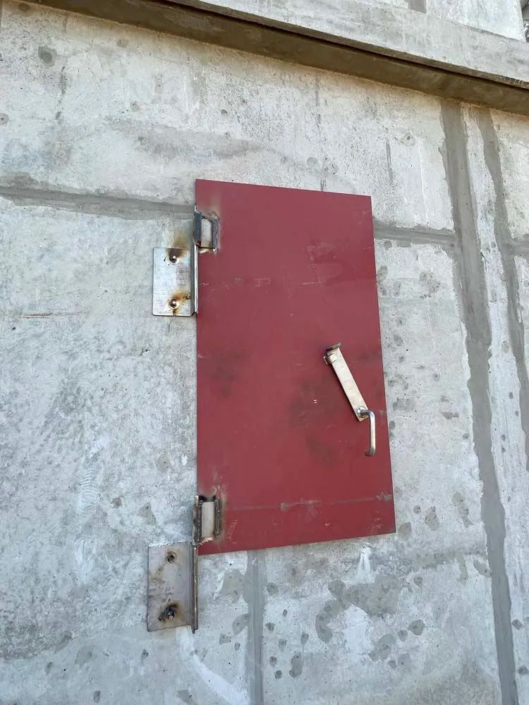 A red door is hanging on a concrete wall