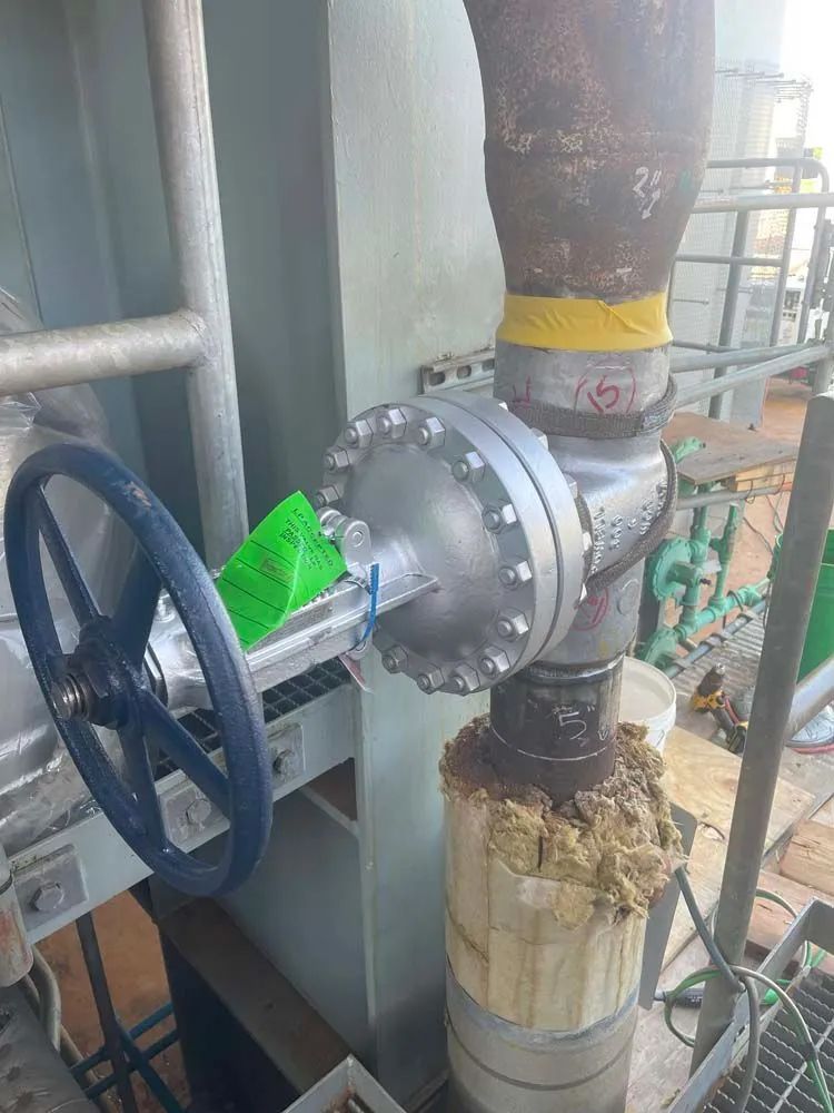 A valve with a blue wheel is attached to a pipe in a factory