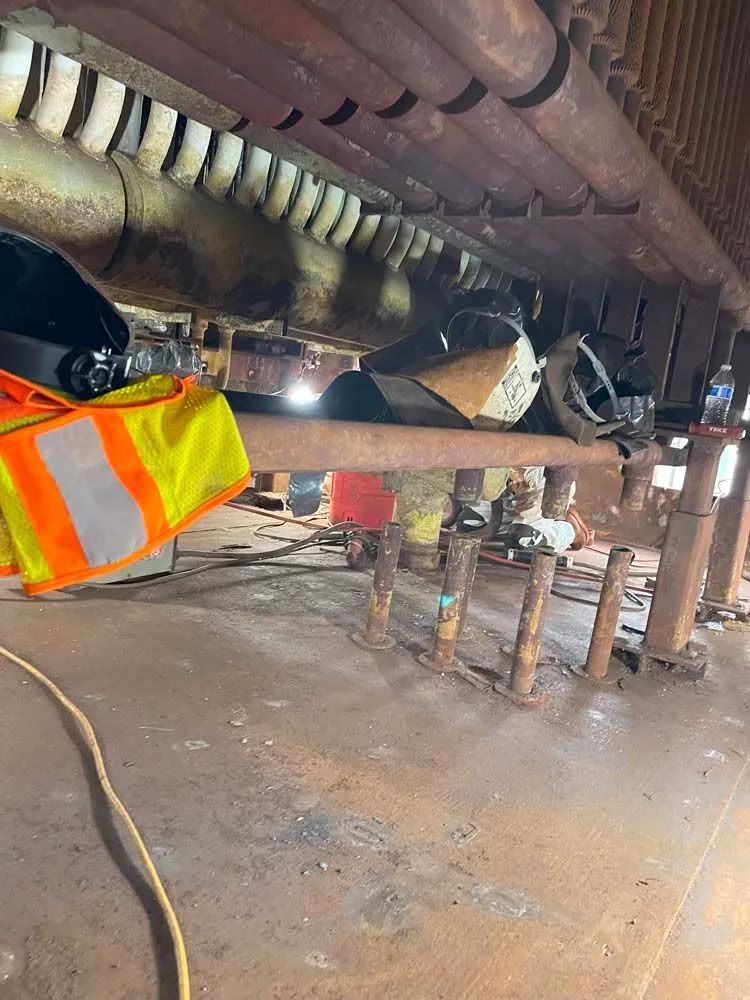 A man is welding a pipe in a factory