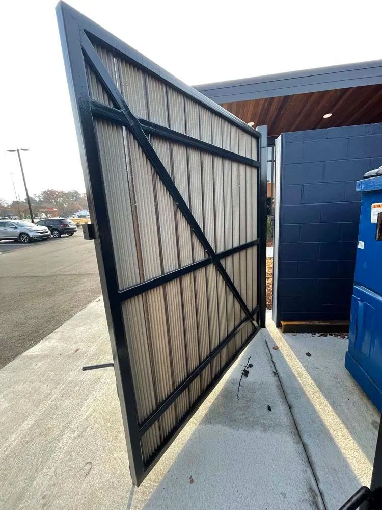 A large metal gate is open to a parking lot