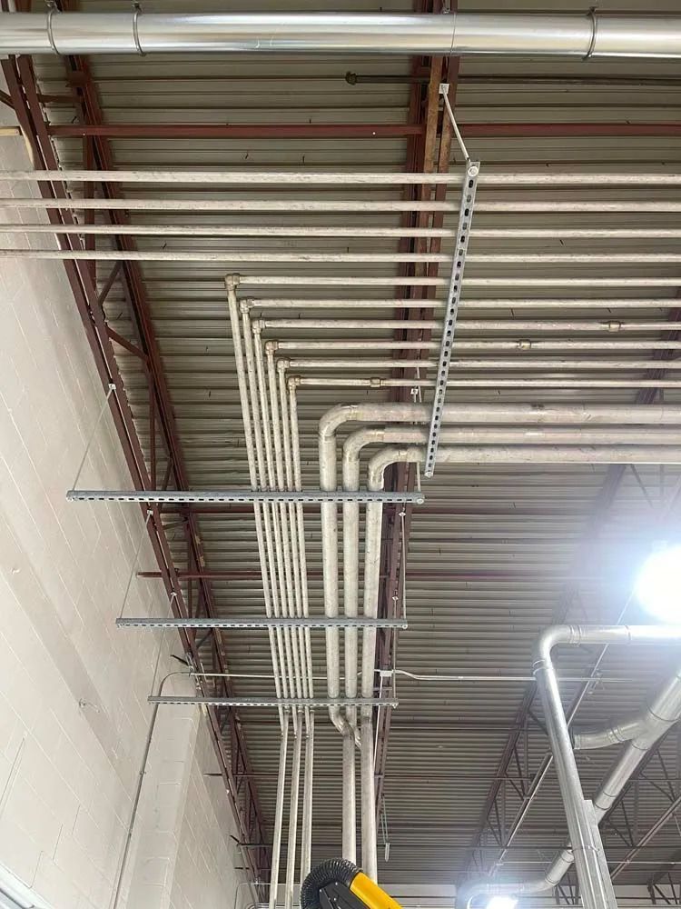 A bunch of pipes are hanging from the ceiling of a building