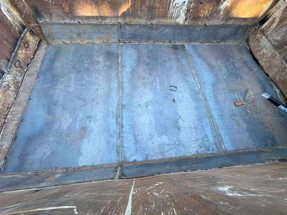 The inside of a dumpster with a metal plate on the floor