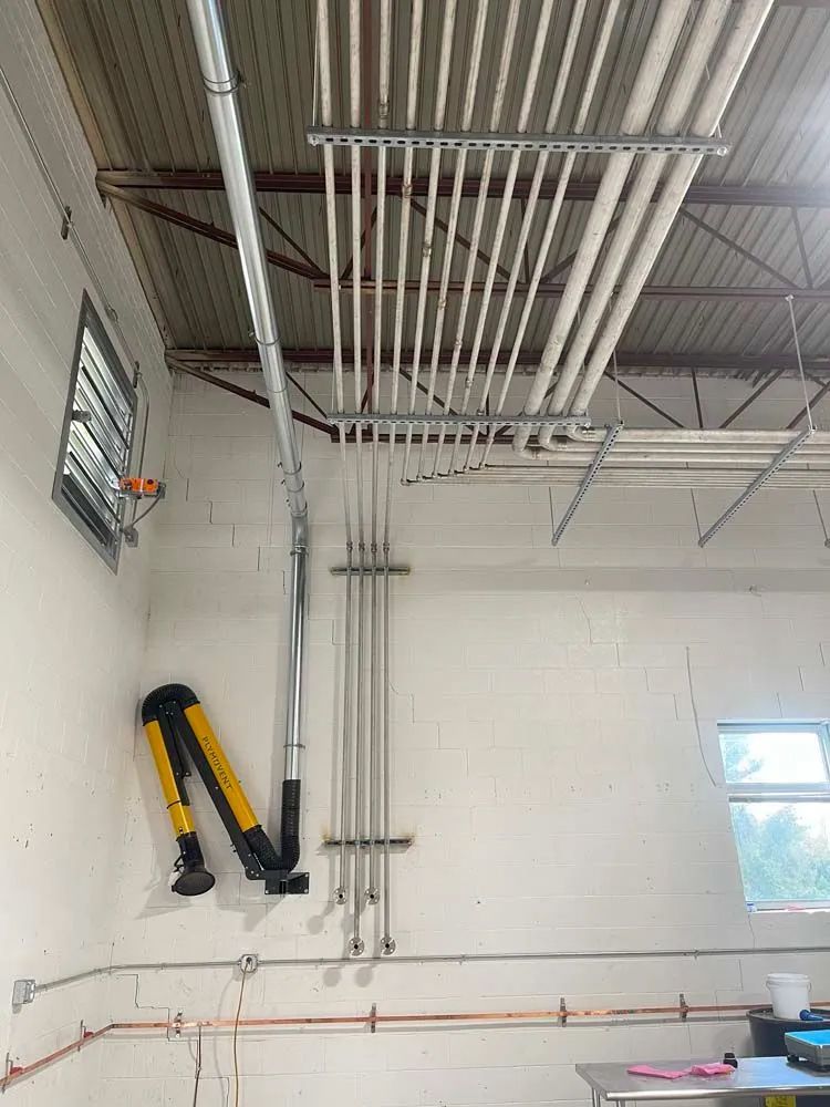 A man wearing a welding helmet is welding a metal object in a warehouse