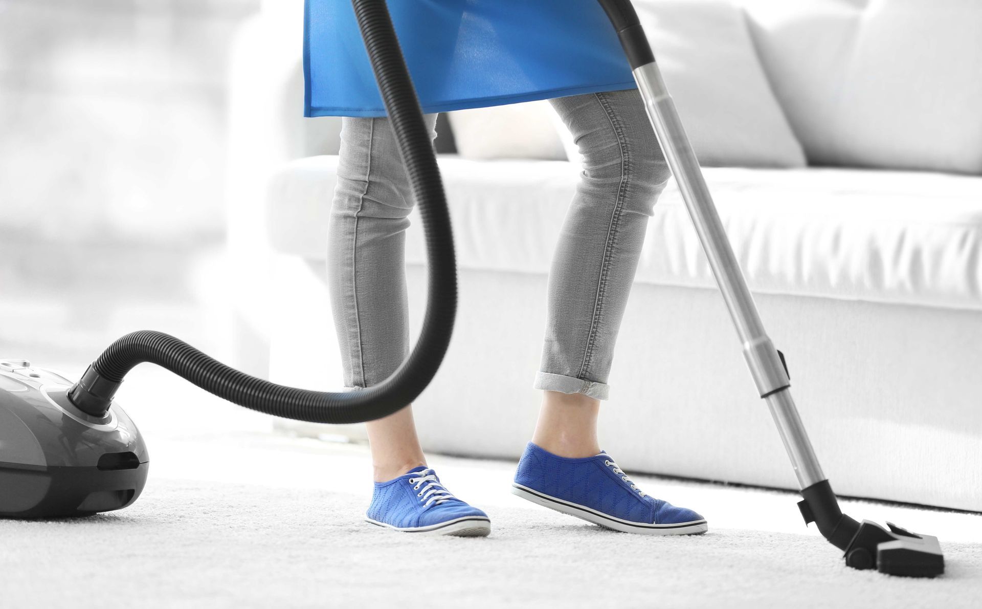 A woman is using a vacuum cleaner to clean the carpet in a living room