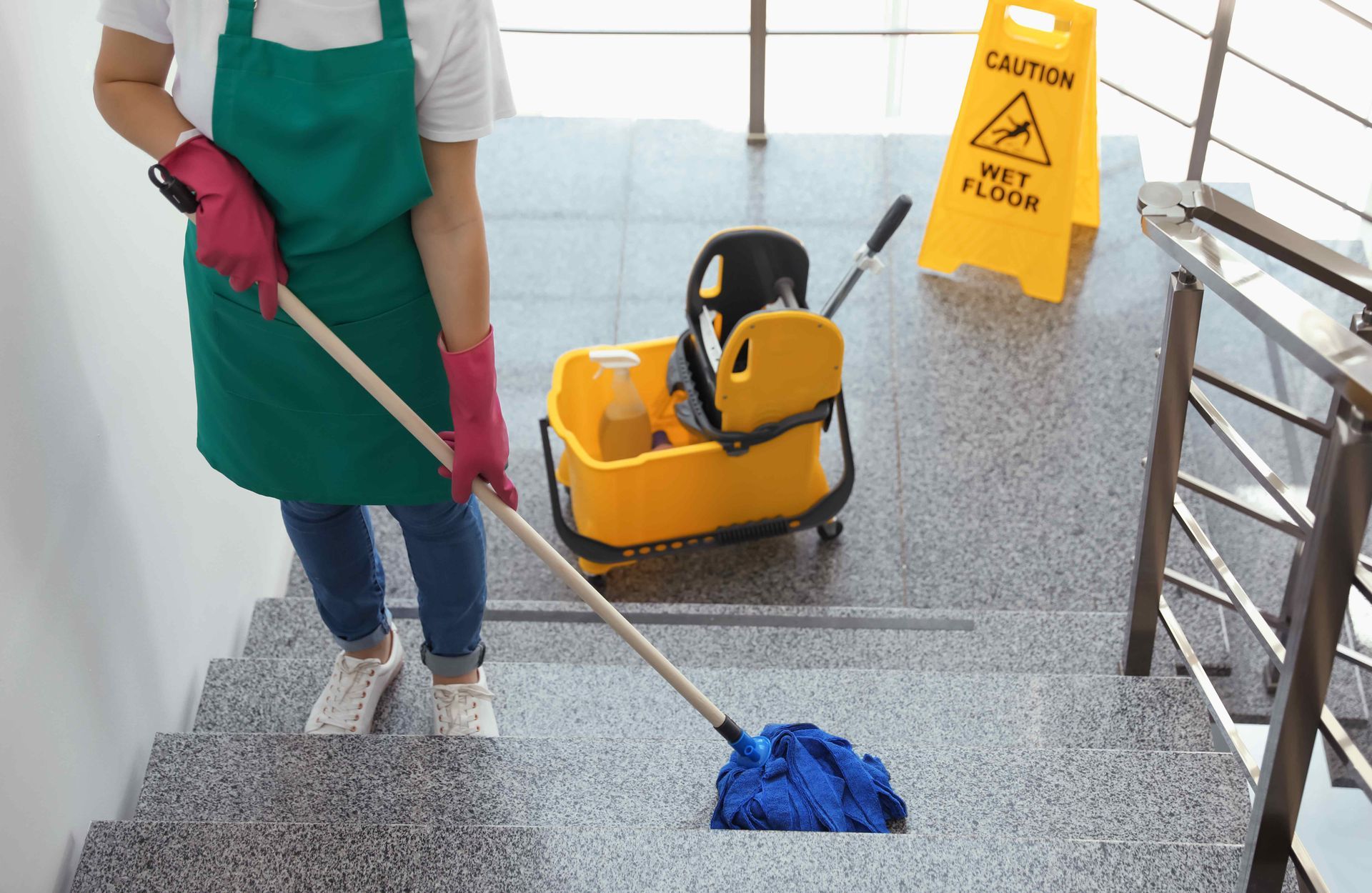 A woman is cleaning a wet floor with a mop