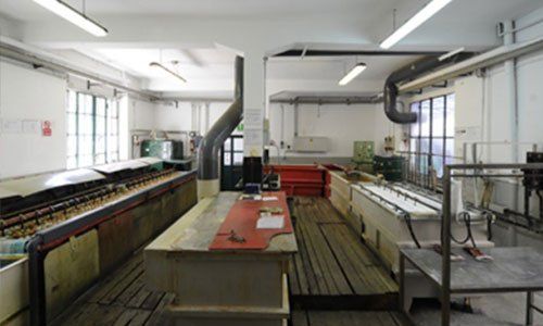 interno di un’ industria di cromature con banchi di lavori in legno e tubature di macchine industriali a Milano