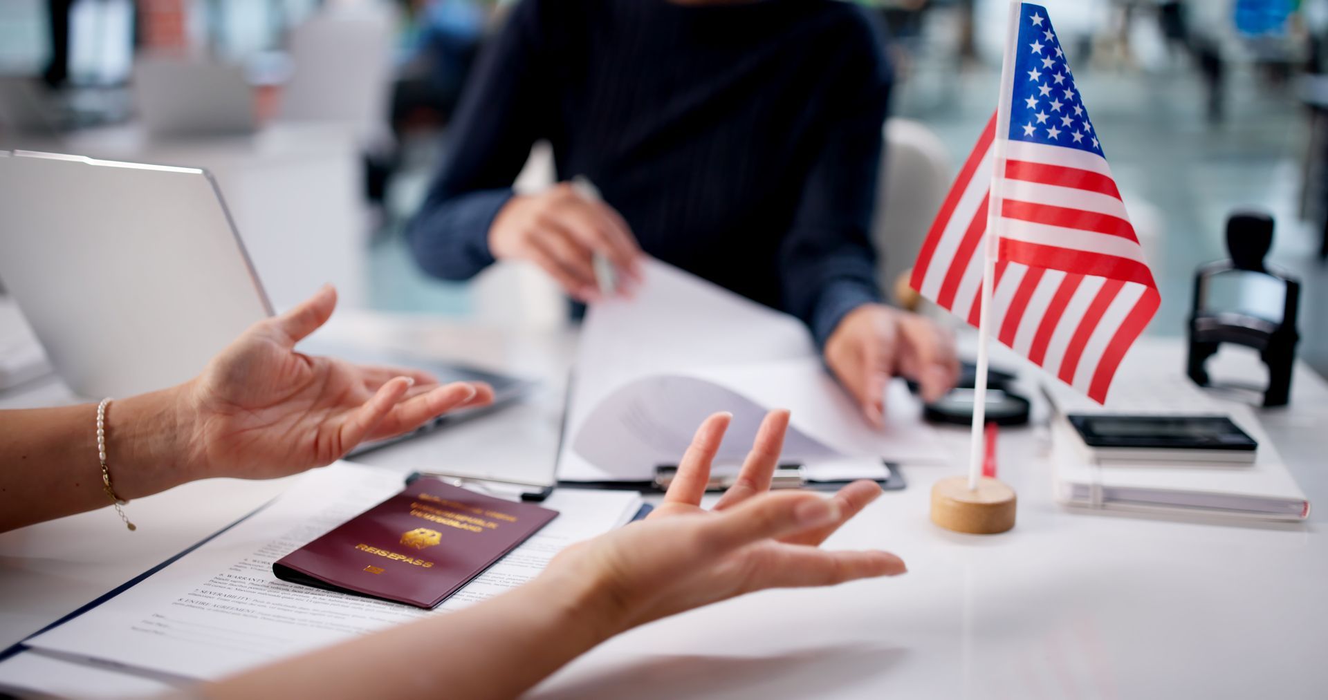 Immigration attorney Elizabeth reviewing visa papers with client and US flag on desk.