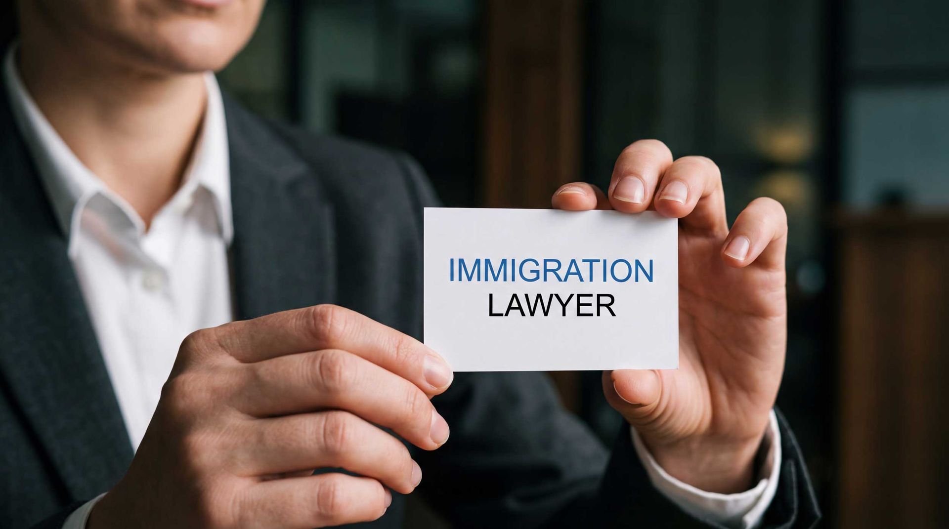 Professional immigration attorney holding a business card for legal services.