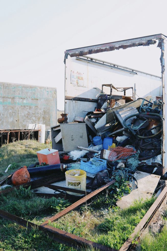 Junk and other debris spilling out of an open shed onto the ground