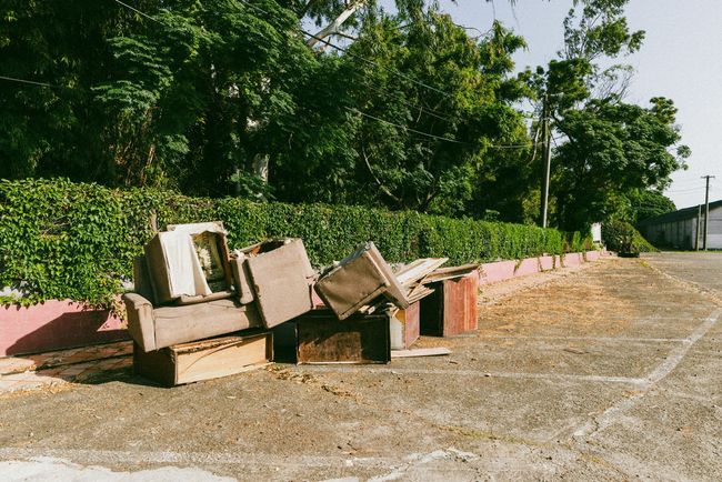 Couch and desk parts outside on the ground in vacant area