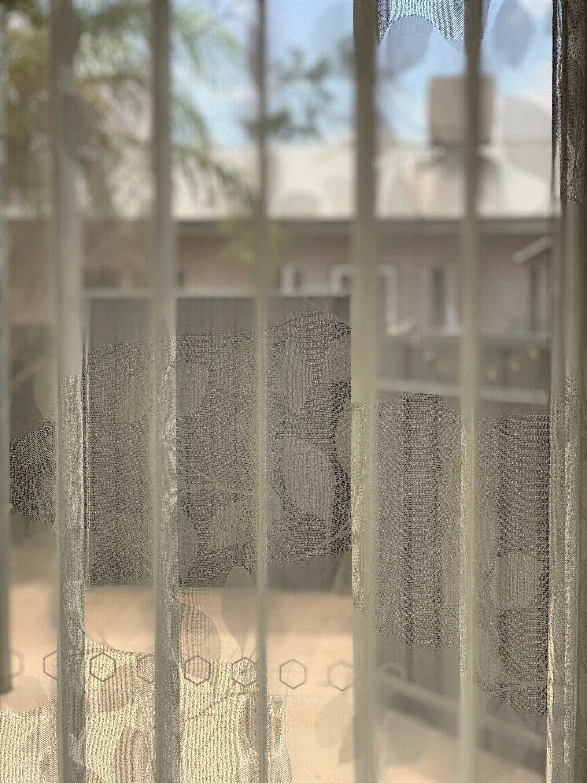 Sheer Curtain Over a Window with A Blurry View of A Building — Alice Mobile Blinds in Ciccone, NT