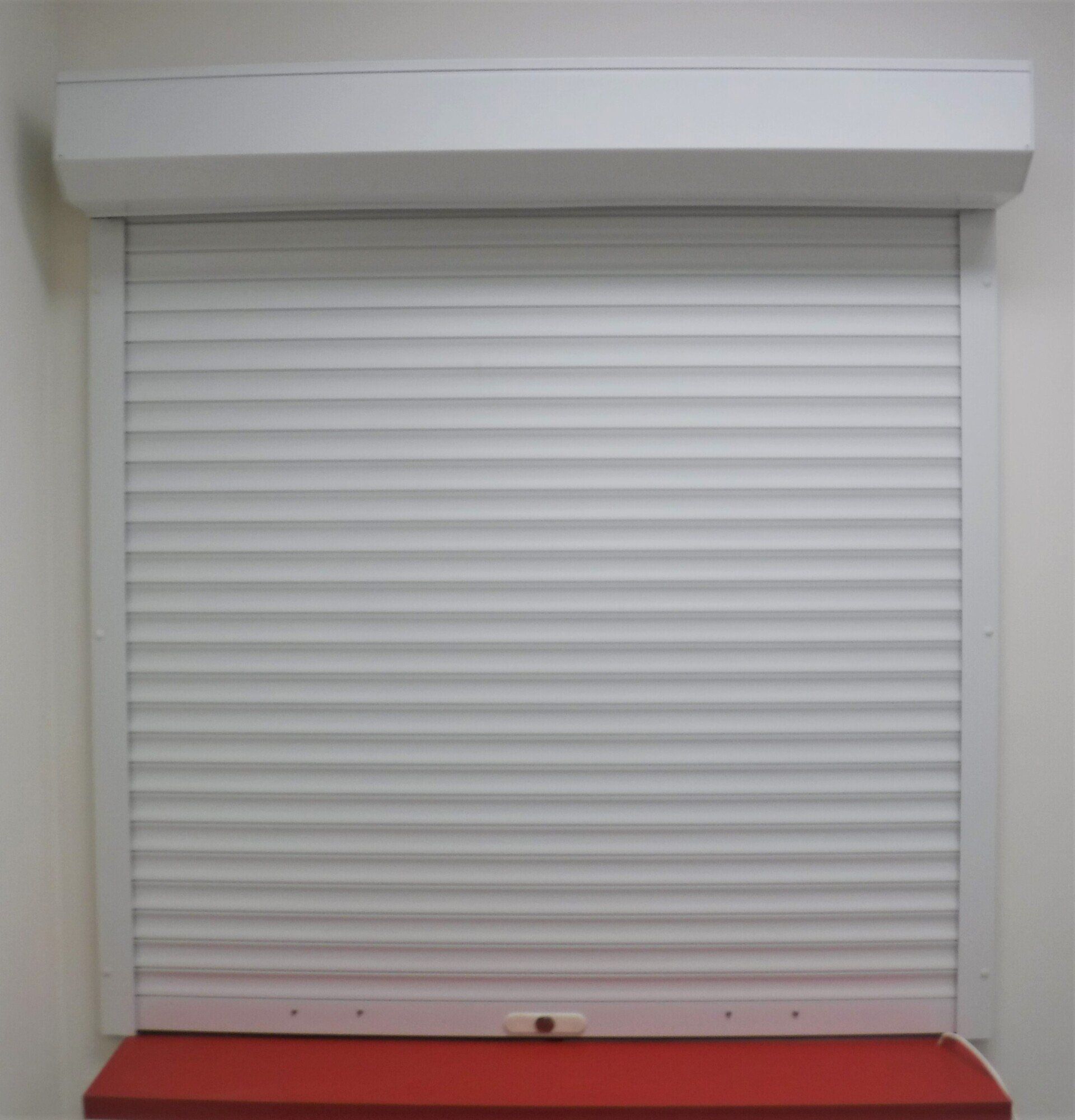 White Closed Rolling Shutter Mounted on A Window Frame with A Red Ledge Beneath — Alice Mobile Blinds in Ciccone, NT