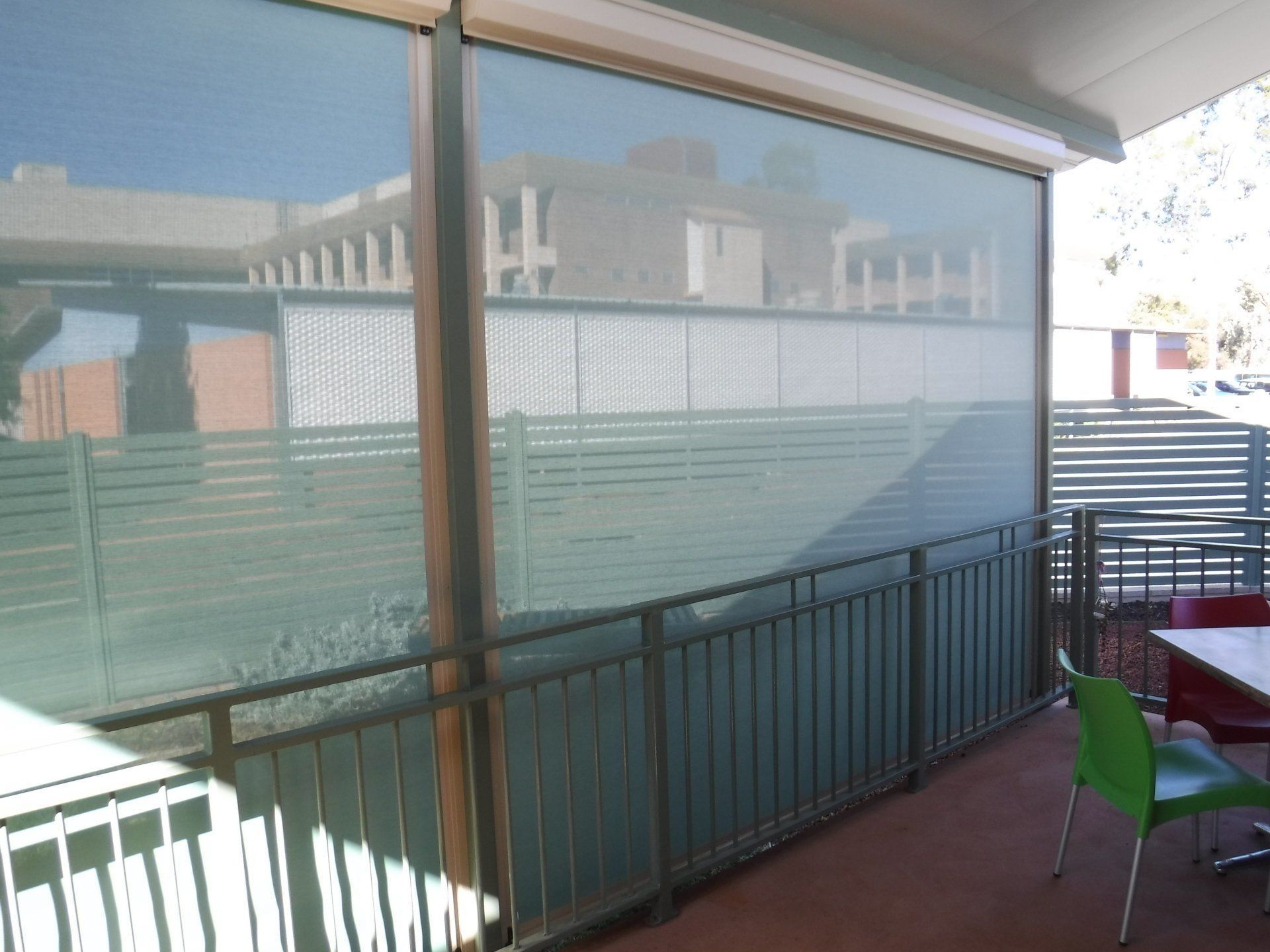 Outdoor Area with Shade Screen, Railing, Green Chair and Table — Alice Mobile Blinds in Ciccone, NT