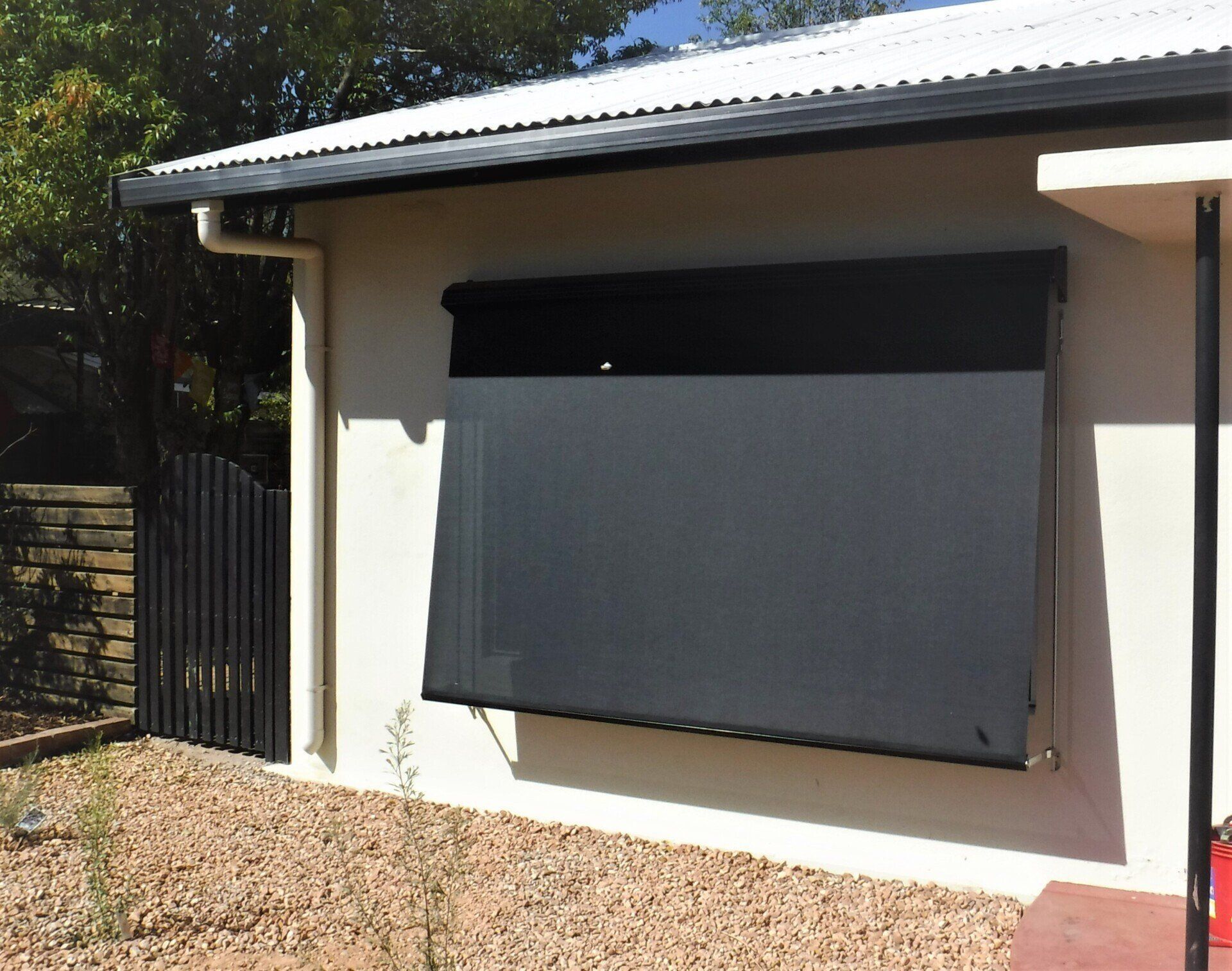 Black Shade on A Building Wall, Beige Exterior and Black Gutter — Alice Mobile Blinds in Ciccone, NT