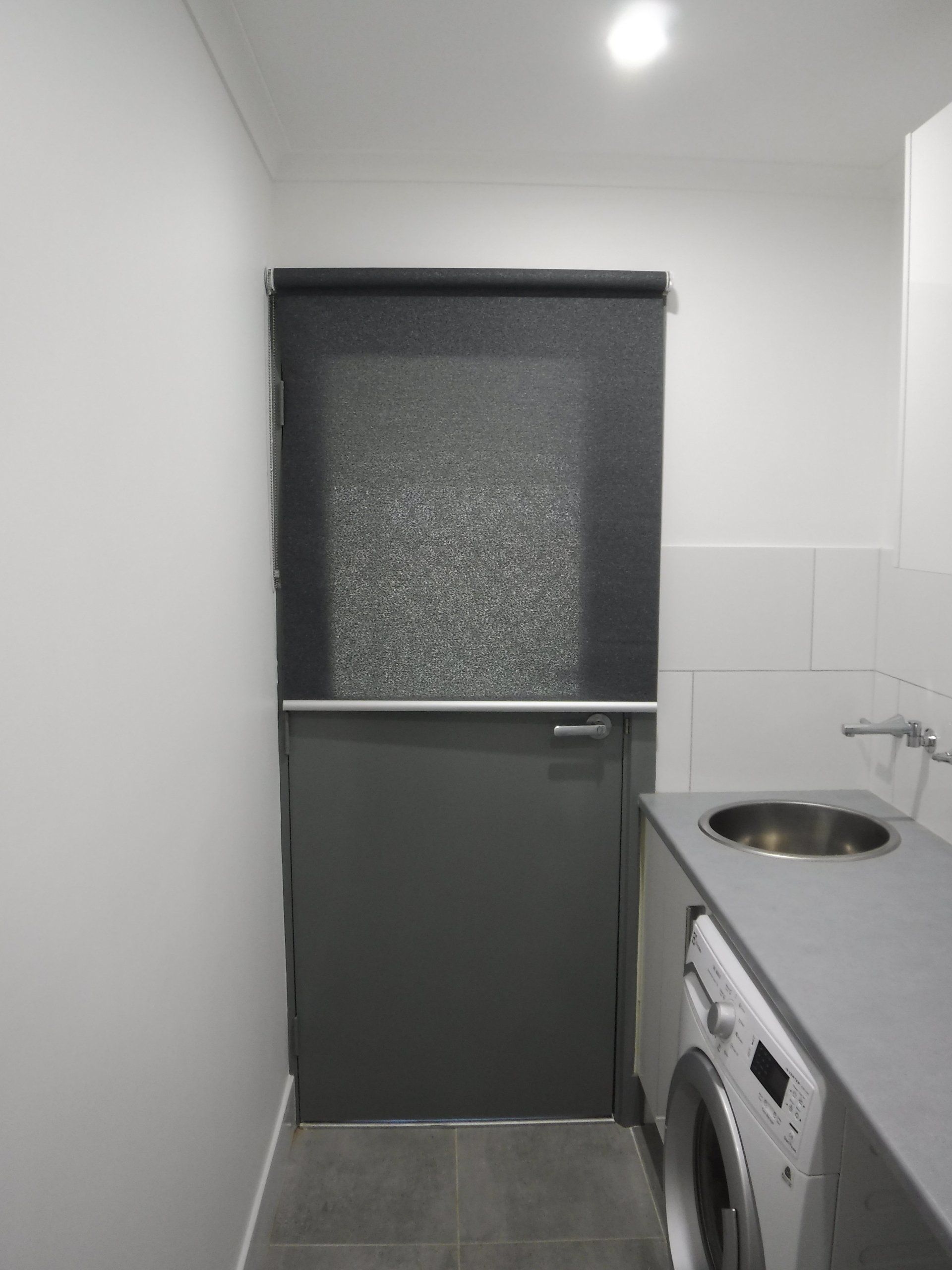 Laundry Room with Grey Door, Window Blind, Washing Machine and Sink — Alice Mobile Blinds in Ciccone, NT