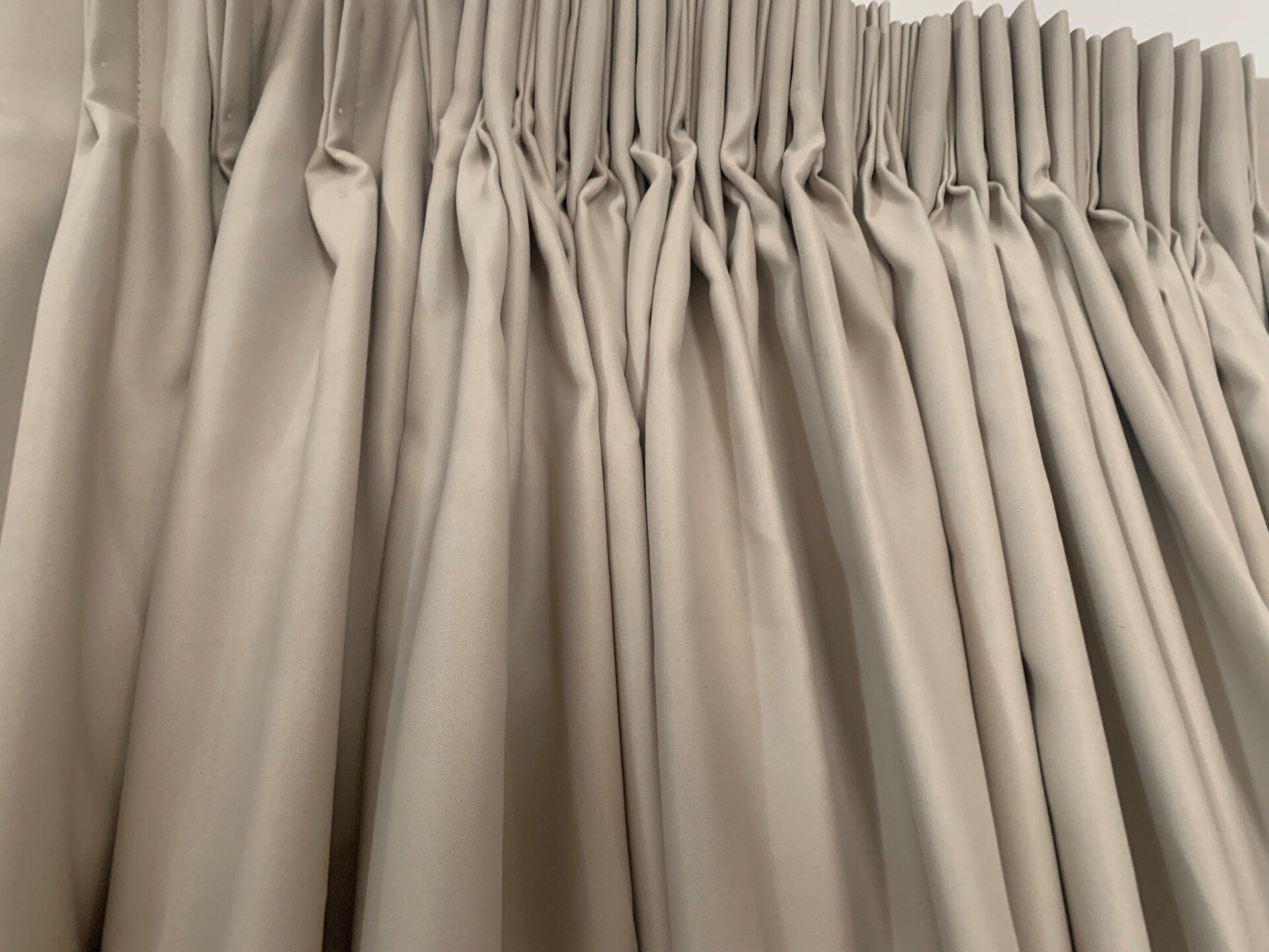 Beige Pleated Curtains Hanging Against a White Wall — Alice Mobile Blinds in Ciccone, NT