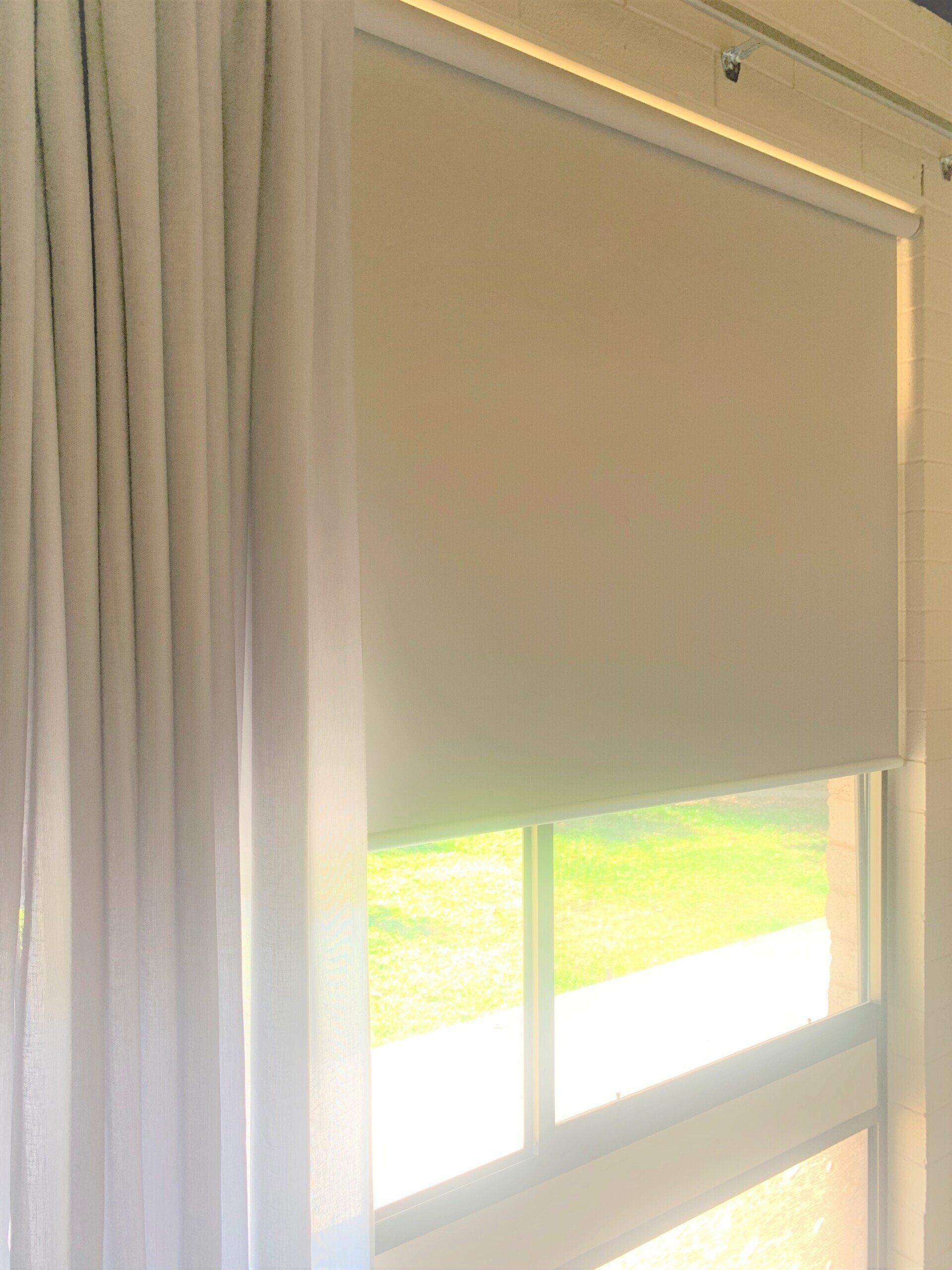 Window with Beige Roller Blind and Light-Coloured Pleated Curtain — Alice Mobile Blinds in Ciccone, NT
