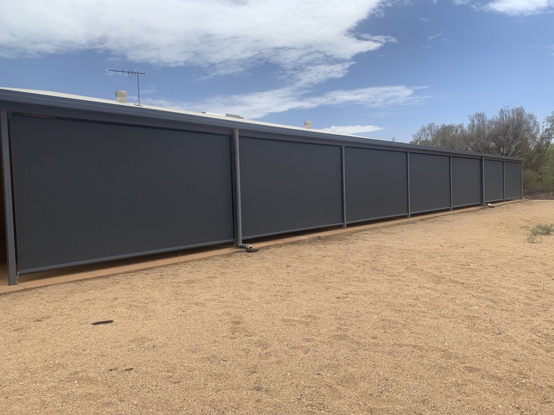 Dark Grey Outdoor Blinds Attached to A Building — Alice Mobile Blinds in Ciccone, NT