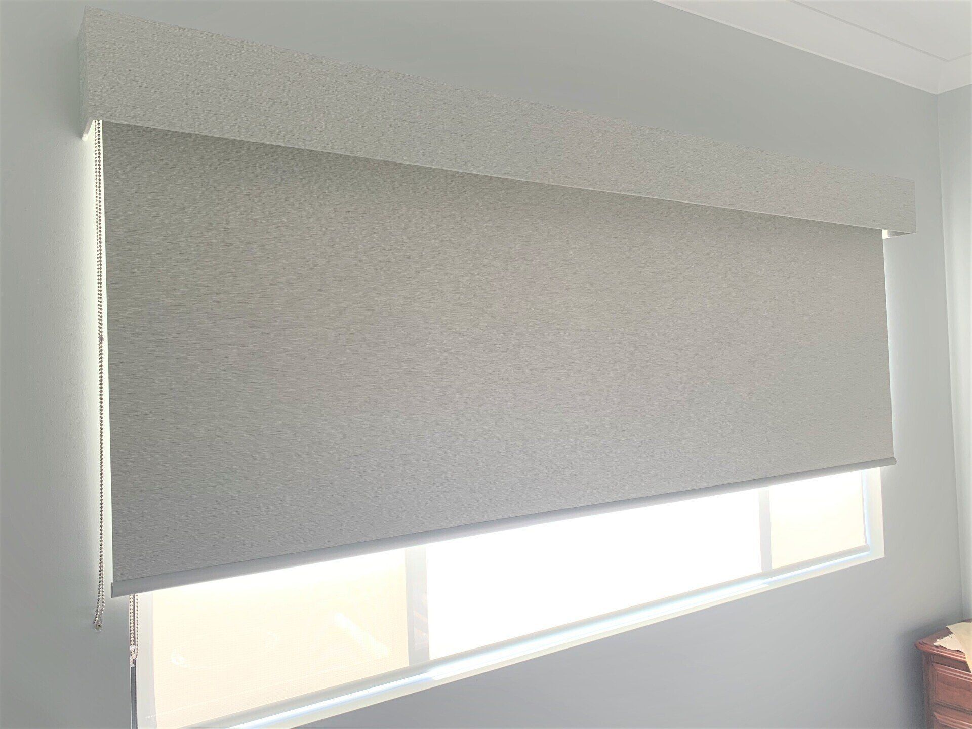 Grey Window Shade Partially Covers Window in Room with Light Blue Walls — Alice Mobile Blinds in Ciccone, NT