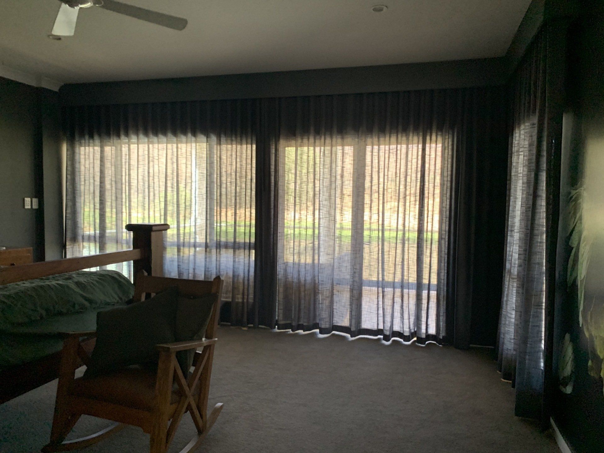 Bedroom with Dark Curtains and A Wooden Rocking Chair — Alice Mobile Blinds in Ciccone, NT