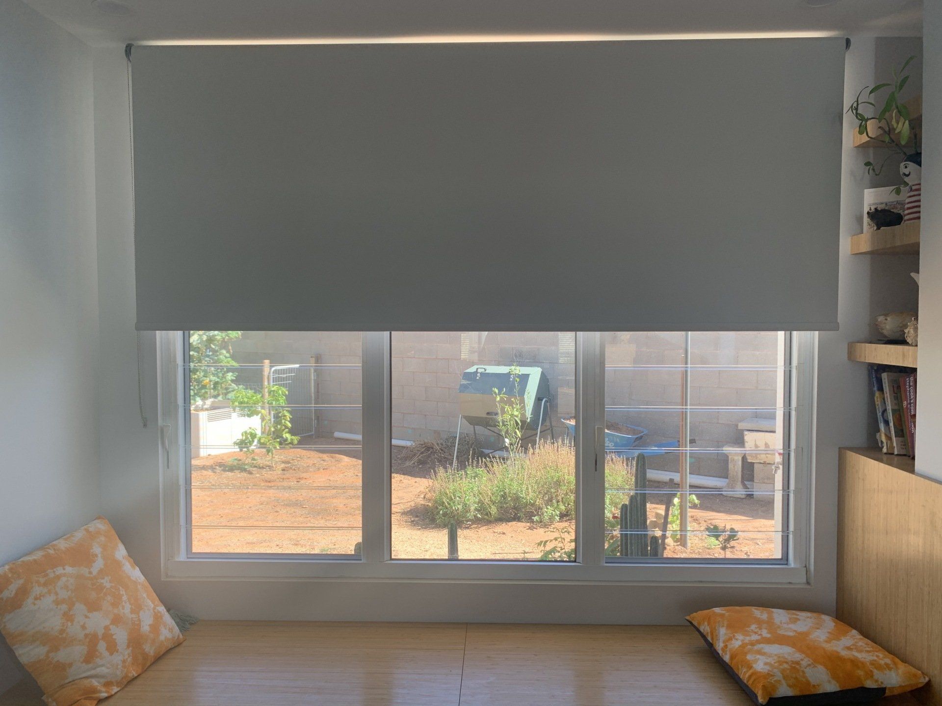 Window Seat with A Partially Lowered Grey Blind — Alice Mobile Blinds in Ciccone, NT