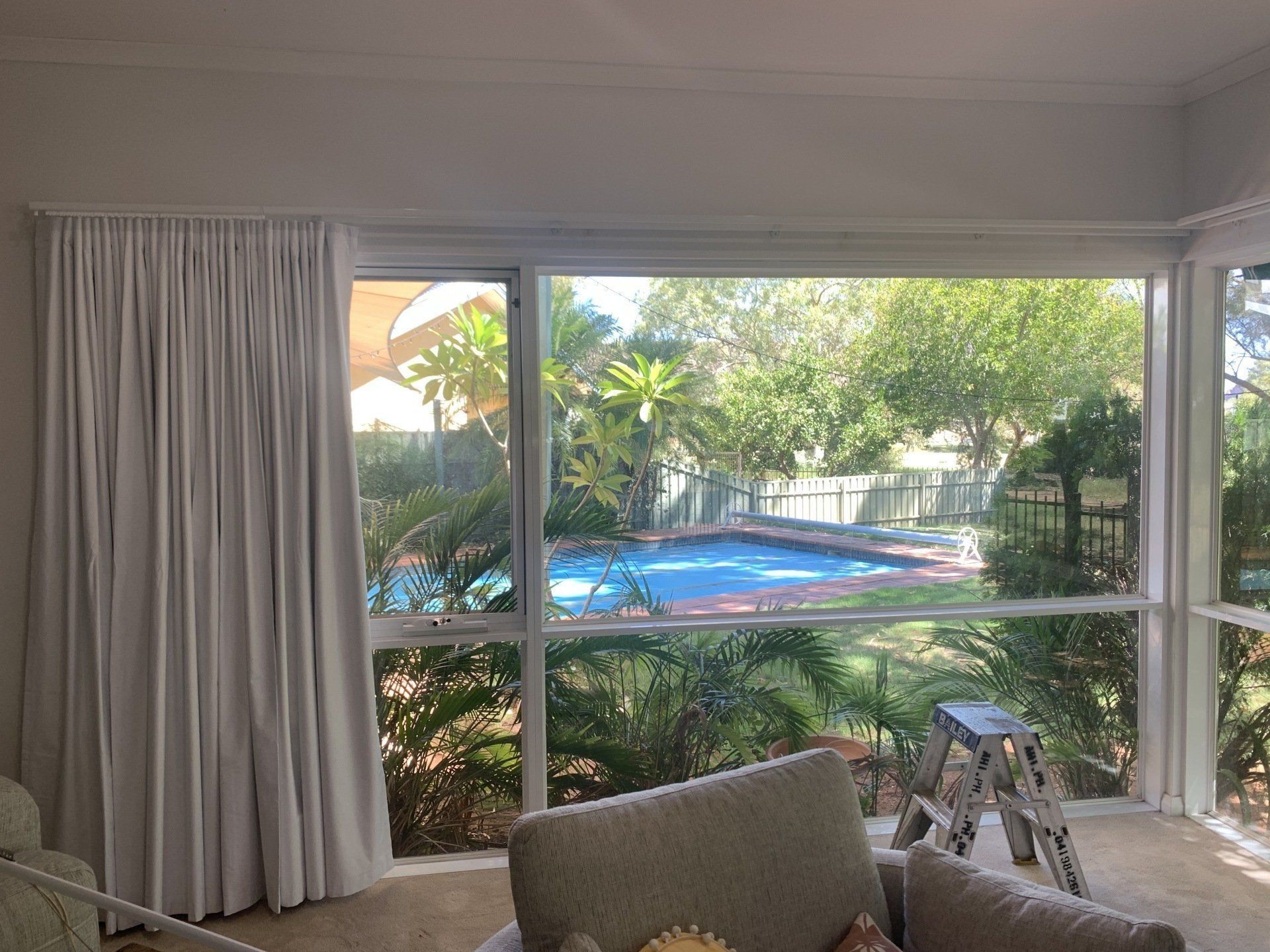 Room with Large Windows Overlooking a Pool and Lush Yard — Alice Mobile Blinds in Ciccone, NT