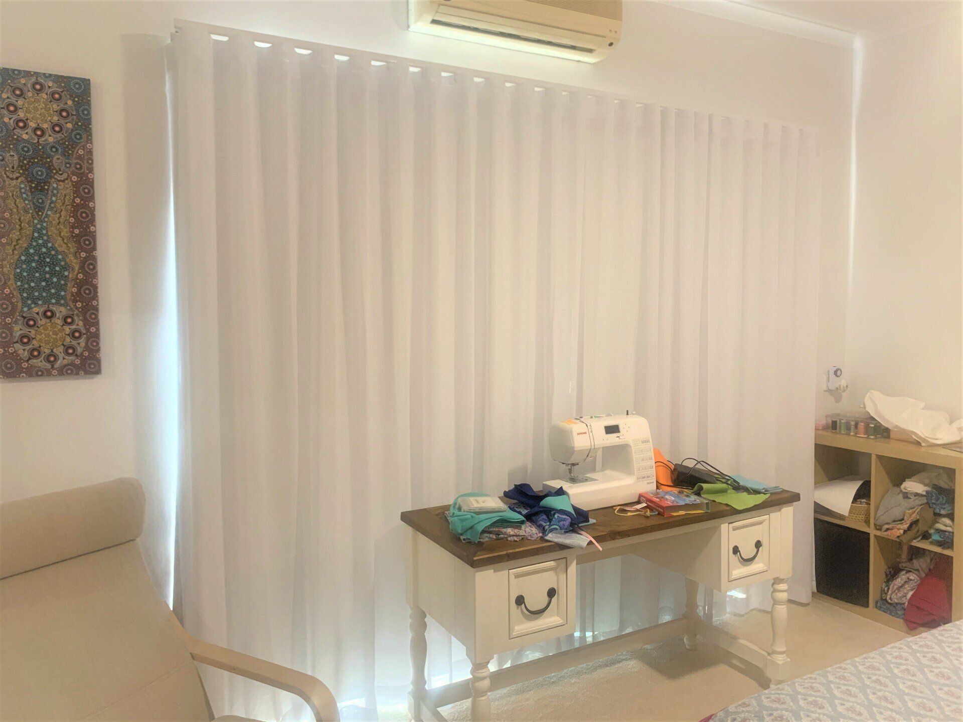 White Curtains Cover a Large Window with A Sewing Table — Alice Mobile Blinds in Ciccone, NT